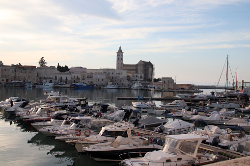 Trani, Province of Barletta-Andria-Trani, Italy - 13 april 2024: the port, with the municipal dock, and the Cathedral of San Nicola Pellegrino, at sunset