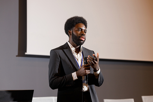 An African man giving a speech at a business technology conference.