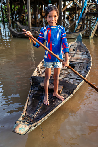 Cambodian girl rowing a boat in village near Tonle Sap, Cambodia