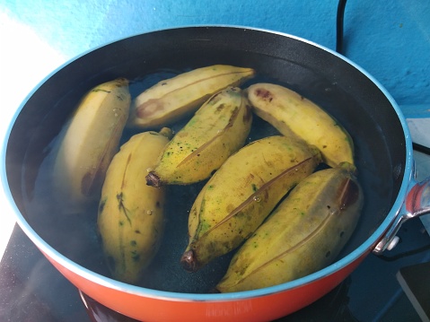 Ripe yellow bananas boiled in hot water with frying pan.