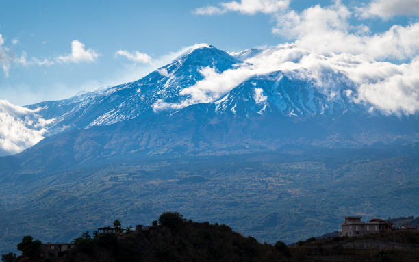 istock View form afar on Etna volcano, Sicily, under a blue sky, with some clouds 2148616148