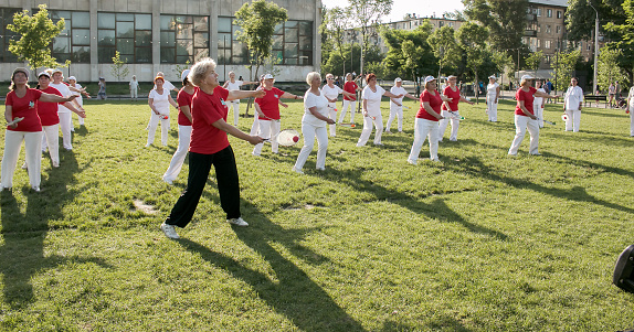 Dnepr, Ukraine - 06.21.2021: Group of elderly people doing health and fitness gymnastics in the park.