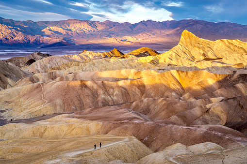 Hikers on the slopes of Zabriskie Point at sunrise in Death Valley National Park in California, United States