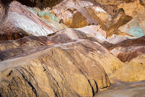 Hikers on the slopes of the Artists Palette in Death Valley National Park in California, United States