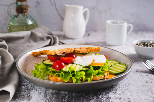 Waffle bread sandwich with poached egg and vegetables on a plate on the table