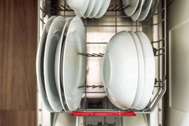 Dirty plates and crockery stacked neatly in the dishwasher in a domestic kitchen.
