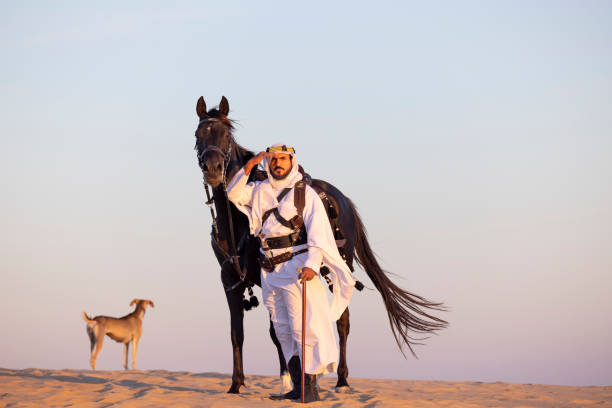 Saudi man with his stallion Saudi man, in traditional clothing, in a desert with his black horse arab man riding horse stock pictures, royalty-free photos & images
