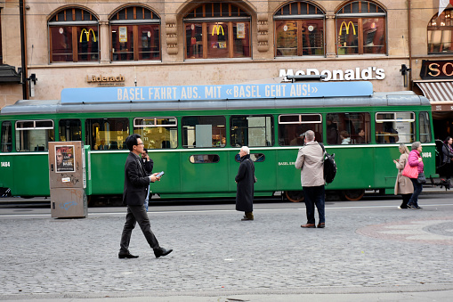 Basel, Switzerland - March 21, 2024: Basel City Public Transportation Tram, Mcdonald's Restaurant, Building Exterior, People Walking, Waiting For Tram Scene And More