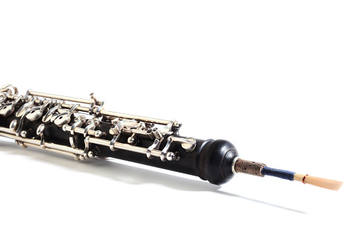 Orchestral woodwind musical instrument - oboe with reed isolated on white