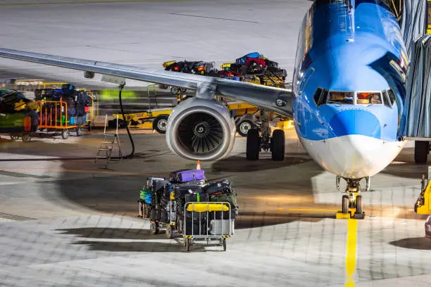 Baggage ground handling on the airport ramp. Workers loading a passenger airlplane with lots of baggage and cargo.
