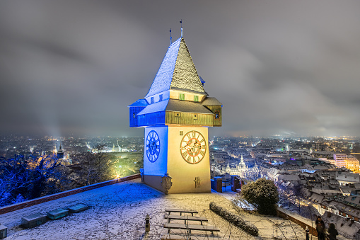 The famous landmark of Graz in Austria, the clock tower at the Schloßberg in winter illuminated with the colors of Ukraine