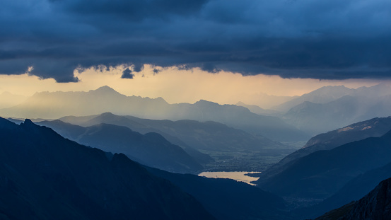 Dark storm clouds over the Hohe Tauern mountain range in Austria. Mystic mood with mountain layers and rays of sun.