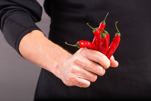 Close-up view of red chili pepper in the hand of a male cook. Episode of the cooking process