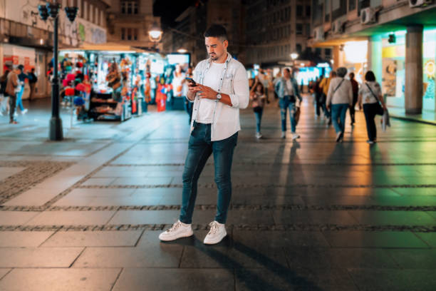 Closeup of male hands typing an sms message via smartphone outside, hipster man enjoying evening walk and using his cellphone
