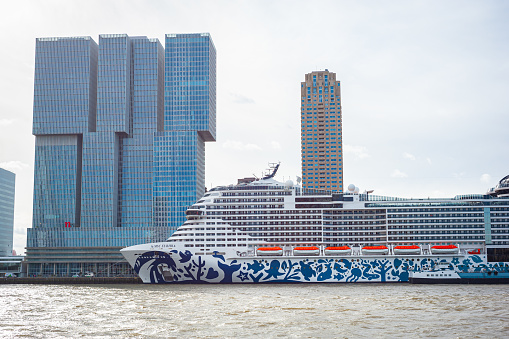 Rotterdam, Netherlands - April 9, 2024: Large cruise ship is docked on the Nieuwe Maas river near Erasmus Bridge in Rotterdam.