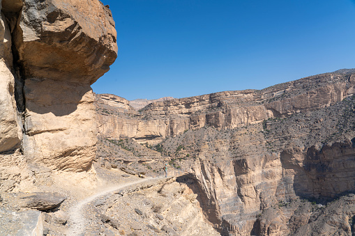 Footpath at edge of Balcony Walk above Wadi Nakhar, Jabal Shams on sunny day and clear sky, Oman