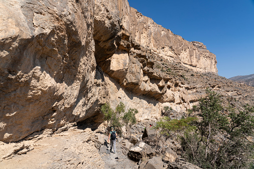Female hiker at edge of Balcony Walk above Wadi Nakhar, Jabal Shams, Oman