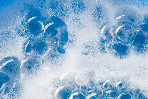 Close-up of soap sud (bubbles foam) on a blue water.