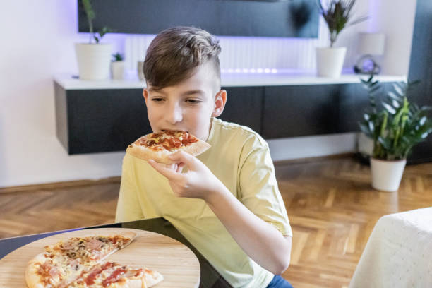 istock Cute boy is enjoying a slice of pizza at home. 2148629896