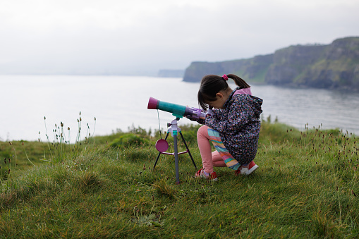 young girl playing moonscope kids telescope on the cliff in the UK