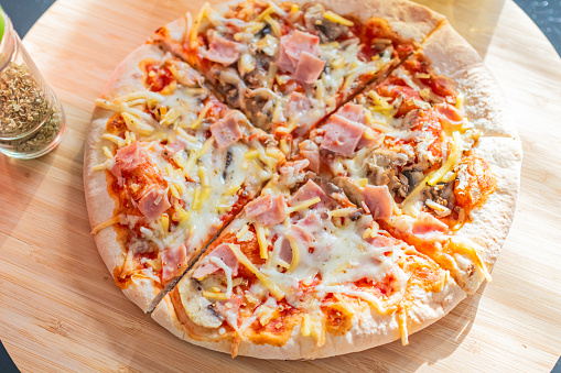 Tasty pizza with ham and cheese.