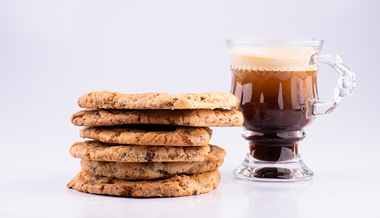 cup of espresso isolated on white background close-up with stack of chocochip cookies in front