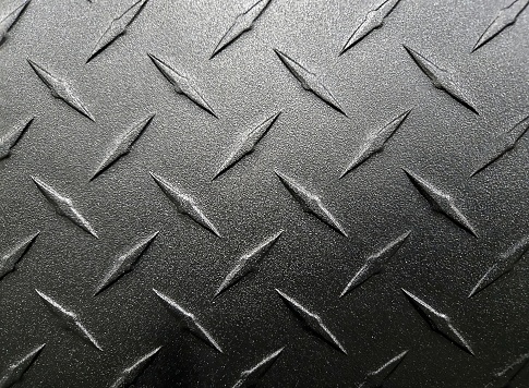 Extreme close-up of dark gray industrial brushed metal diamond plating