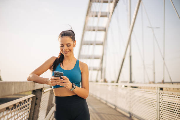 istock Attractive sportswoman standing on a bridge and using a smartphone to write a message. 2148634560