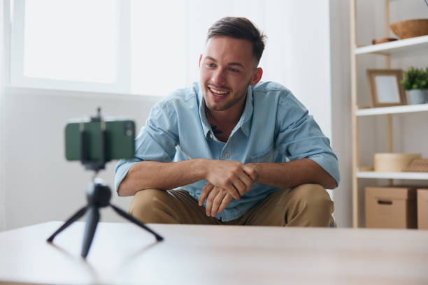 istock Cheerful smiling attractive influencer blogger talking with students audience using phone at home table. Copy space for ad. Electronic IT PC accessories ad. Gadget addiction Online education concept 2148634997