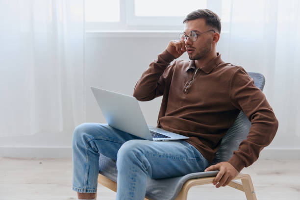 istock Modern Profession offer. Pensive young man in eyewear typing report for work project think about right decision for work screen sitting in chair at home. Remote Job Distant Work Communication concept 2148635066