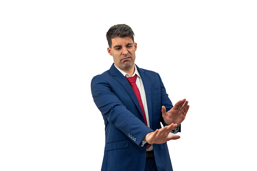 businessman he extends his hands forward and downward in a rejection gesture, while displaying a contradictory facial expression. he embodies corporate rejection and confusion white background