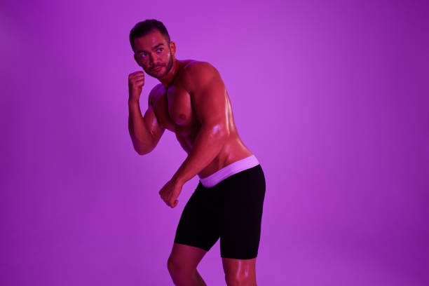 istock Man athletic bodybuilder poses with nude torso abs in full-length background, boxing and martial arts. Advertising, sports, active lifestyle, color light, competition, challenge concept. 2148640631