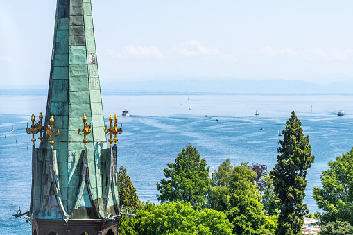 Description: View of the Münster Ostturm and the lake with steamers and sailing boats on a sunny summer day with mountain panorama. Constance, Lake Constance, Baden-Württemberg, Germany, Europe.