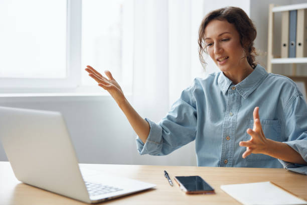 istock Furious angry evil beautiful curly businesswoman hates computer crash having problem with broken laptop swings at gadget raises hands up sitting at home office. Freelancer work concept. Copy space 2148641899