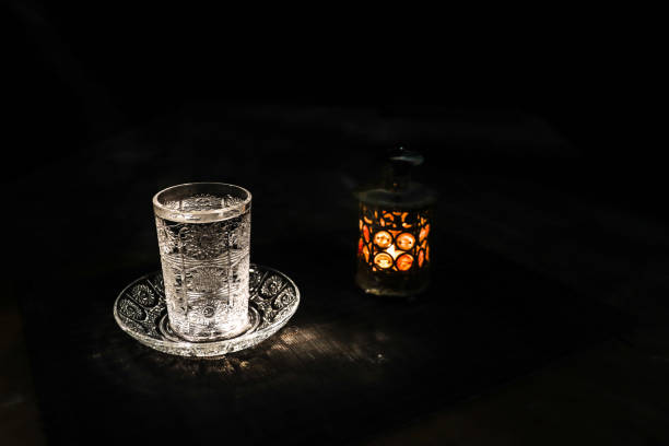 Suhoor or iftar time during Ramadan fasting. A glass of water and dates to break the fast. Festive greeting card, invitation for Muslim holy month Ramadan Kareem. Selective focus