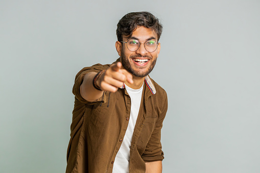Happy Indian young man laughing out loud after hearing ridiculous anecdote, reaction on funny joke, feeling carefree amused. Positive people lifestyle. Arabian guy isolated on studio gray background
