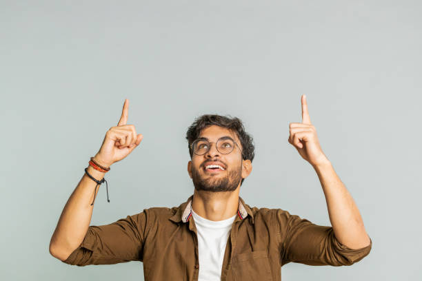 istock Young man showing thumbs up and pointing overhead on blank space place for your advertisement logo 2148644146
