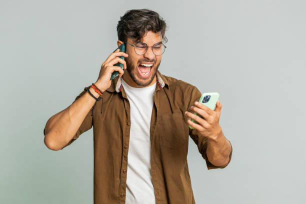 istock Irritated stressed business man talking on two mobile phones having conversation conflict quarrel 2148644184