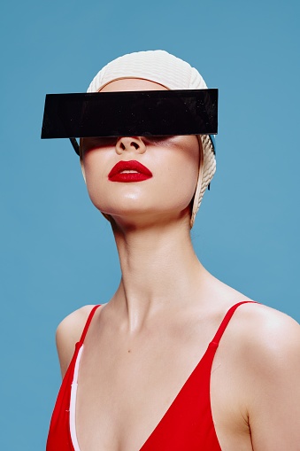Censorship. A stylish red-lipped lady in a red swimsuit with hidden eyes looks up. Art fashion concept. High quality photo