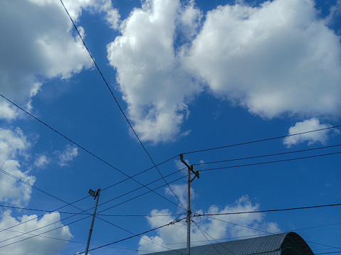 sky scape of electric cable line, white cloud on day blue sky background