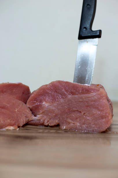Piece of raw ham with knife on the wood table. Vertical format