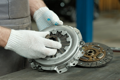A new clutch kit is in the hands of an auto mechanic. Control of the serviceability of the leading, driven and exhaust bearings.