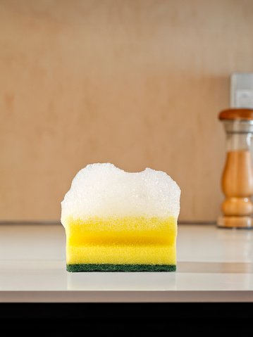 Sponge with soap sud on a kitchen counter top