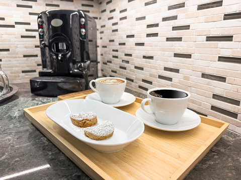 Coffee cups with cookies and coffee maker on a domestic kitchen