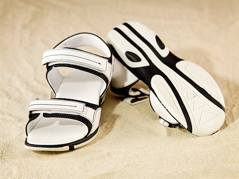 Still life of a pair of white beach sandals on sand