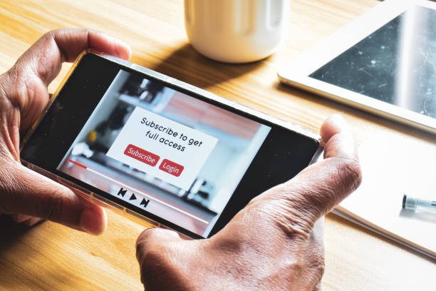 istock Man using smartphone showing a message to subscribe or login to get full access to the video or movie. 2148656437