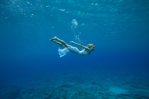 Girl swimming in crystal clear water with dress on