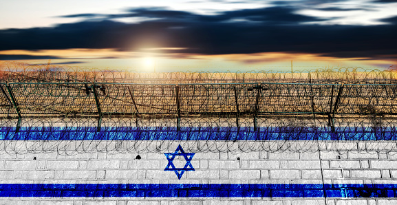 Brick wall with barbed wire in the colors of israeli flag
