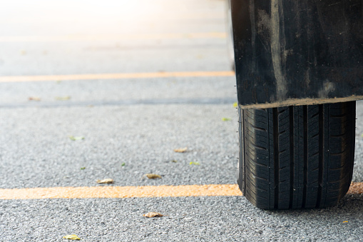 Close of used car tires on asphalt road with sun light in the morning time. With yellow line across the floor.