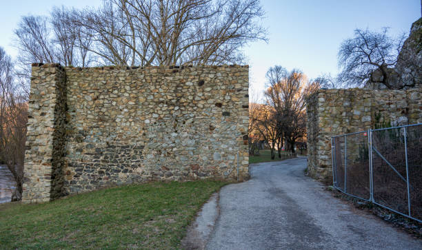 istock Historic stone wall in the forest. Asphalt road. Sunny. 2148662868